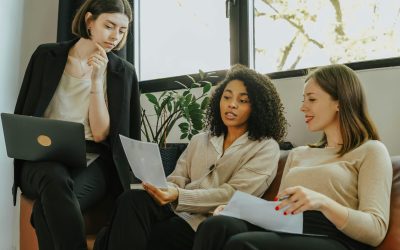 Three professional women engaged in a collaborative meeting in a modern office setting.